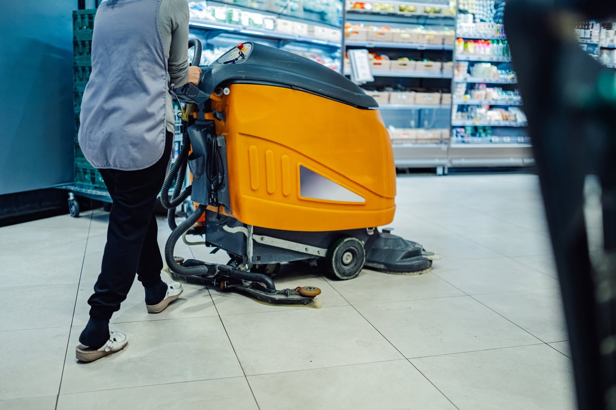 Operaria de limpieza con máquina rotativa manteniendo limpios los pasillos de un comercio