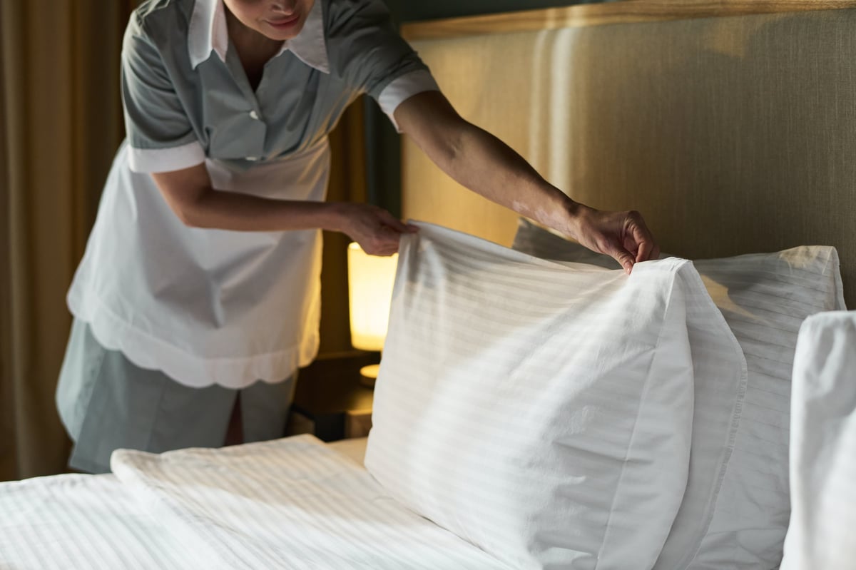 Personal de habitaciones preparando la cama y los detalles de un alojamiento