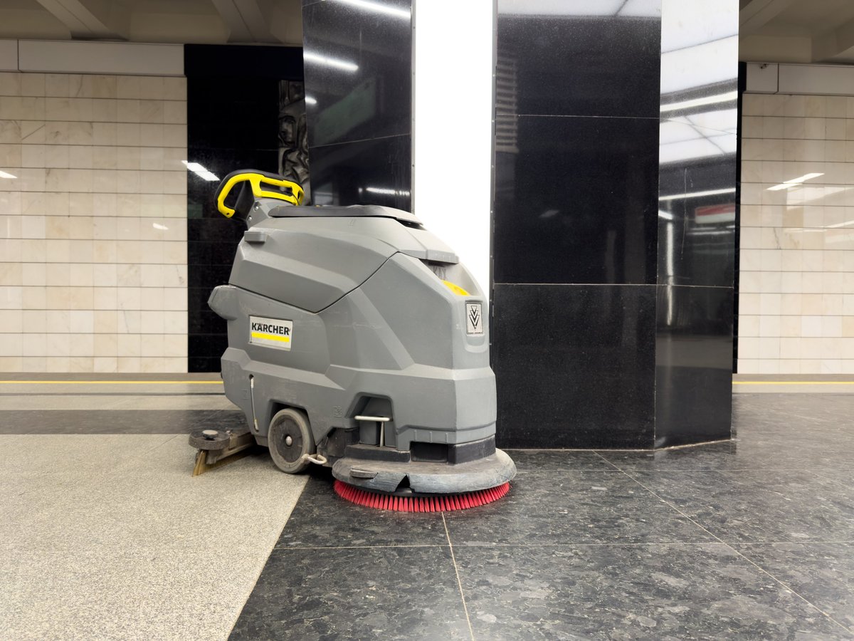 Máquina de limpieza de suelos trabajando en una zona común amplia y luminosa
