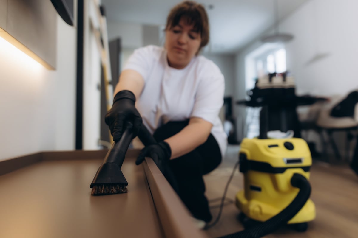 Profesional de limpieza aspirando el polvo de una superficie en una vivienda